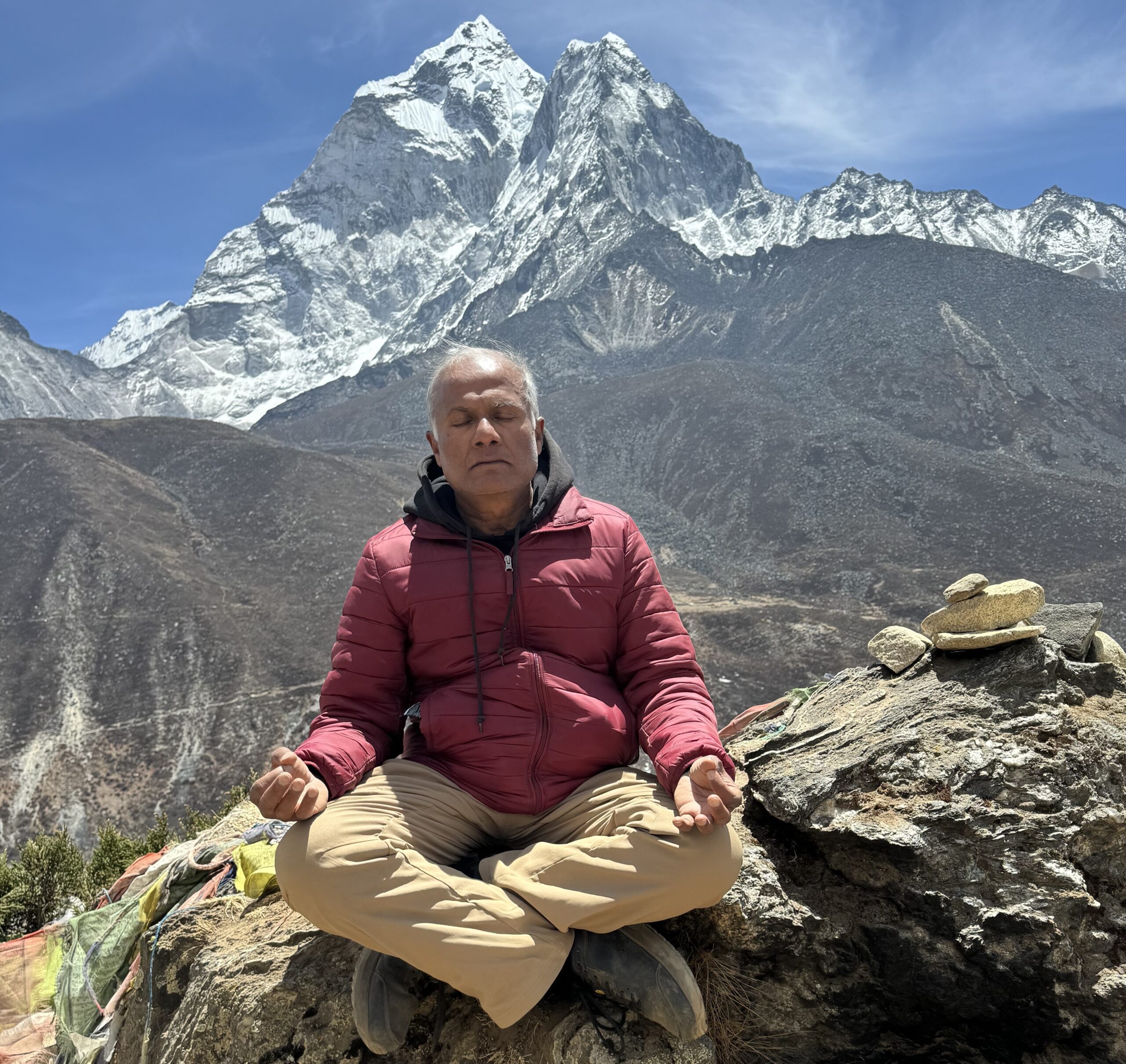 Dr Shrenik Shah meditating at Everest Base Camp with Ama Dablam mountain in the background.
