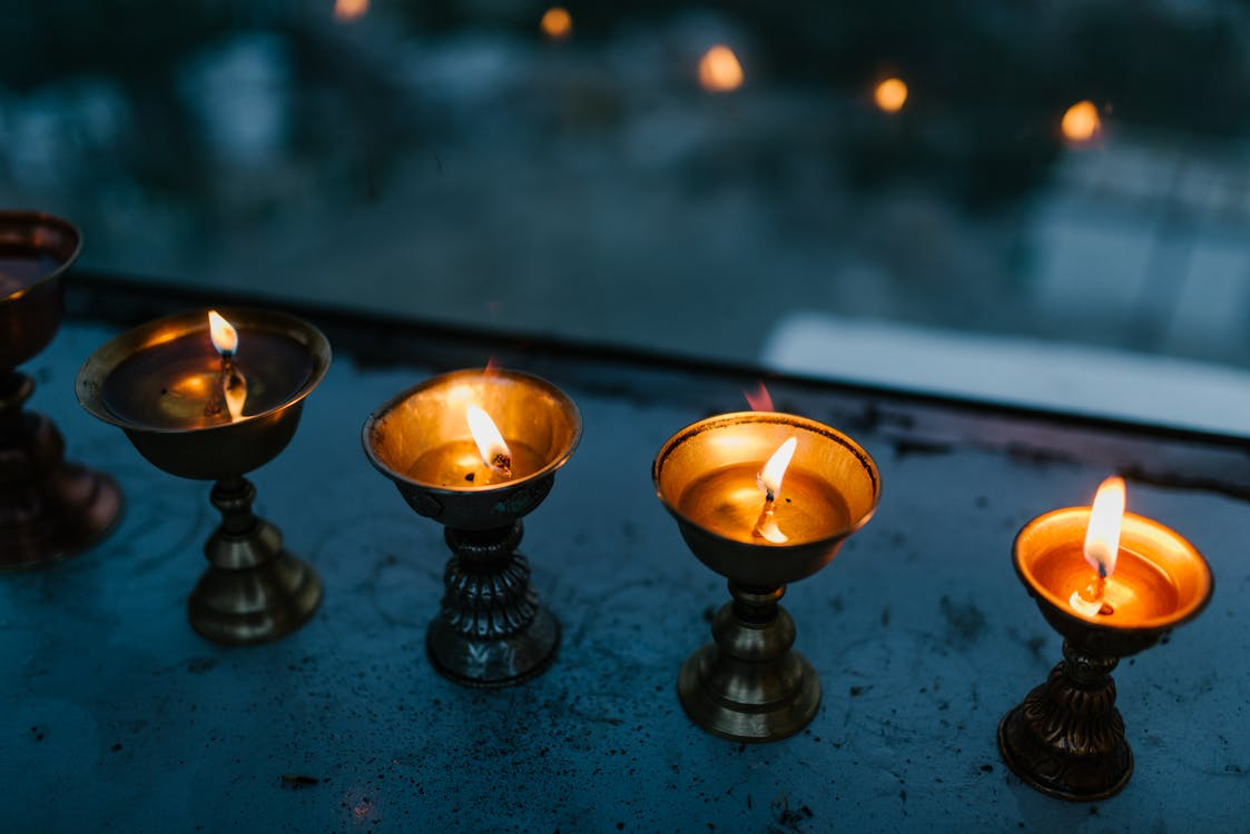 Brass oil lamps (diyas) burning in a row during Diwali, symbolizing light, clarity, and spiritual awakening.