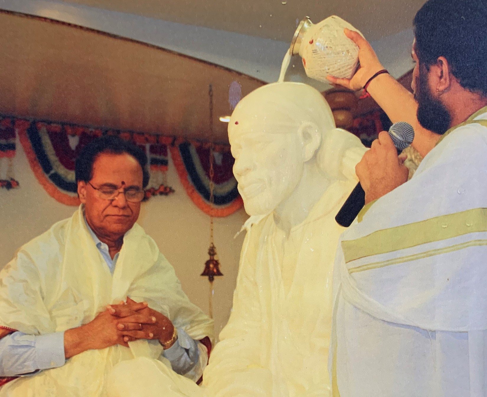 Dr Dattatreyudu Nori in deep devotion as the Sai Baba idol is ritually bathed in a temple he founded.